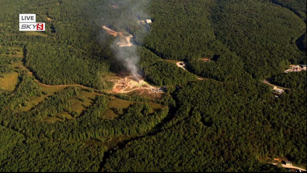 a photograph from New Channel 5 Nashville's helicopter showing smoke rising from where the building in the prior image once stood. the parking lot remains visible in the shot and shows several vehicles which presumably belonged to the victims. 