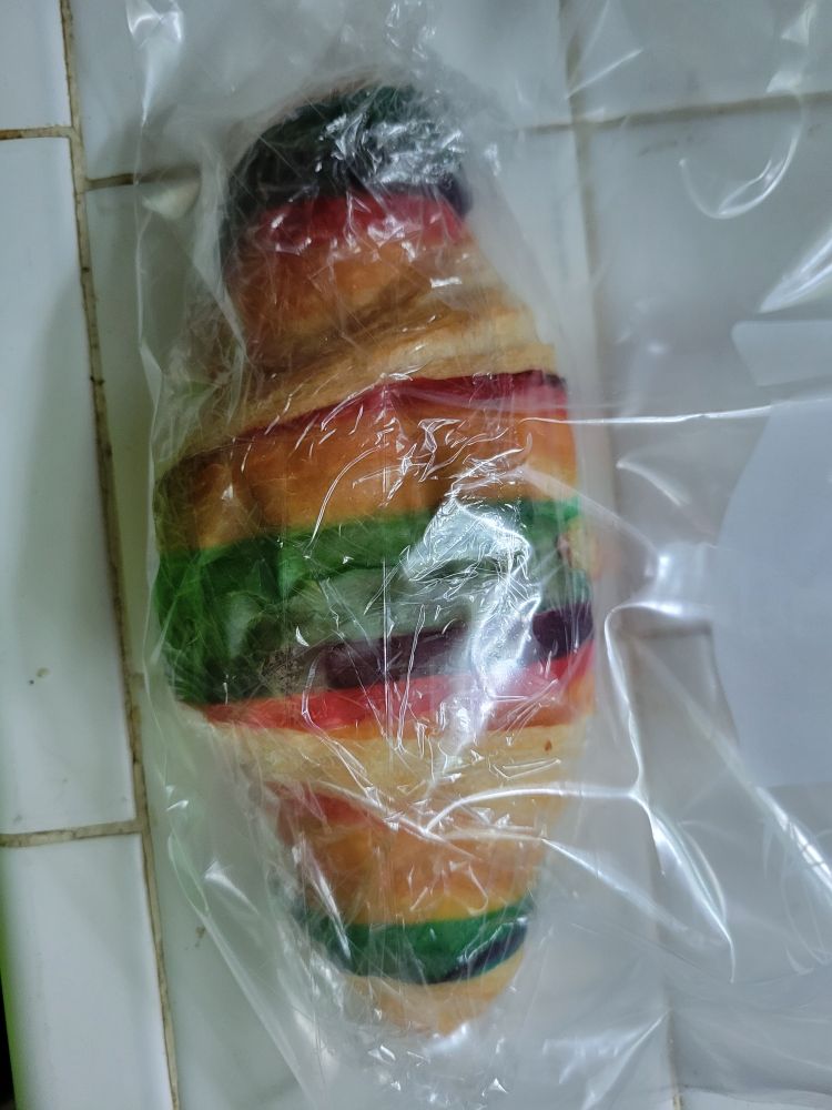 A croissant made with rainbow striped dough. It is a Pride croissant 