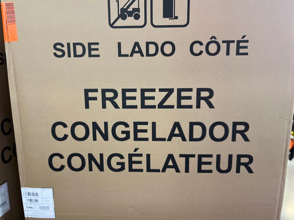 One multilingual panel of a cardboard refrigerator box reading: SIDE LADO CÔTÉ FREEZER CONGELADOR CONGÉLATEUR