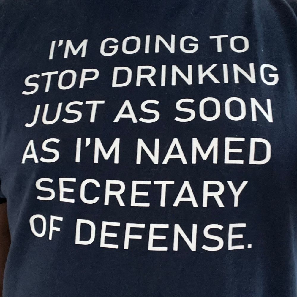 The front of a navy blue T-shirt with white all-caps lettering reading, “I’m going to stop drinking just as soon as I’m named Secretary of Defense.”