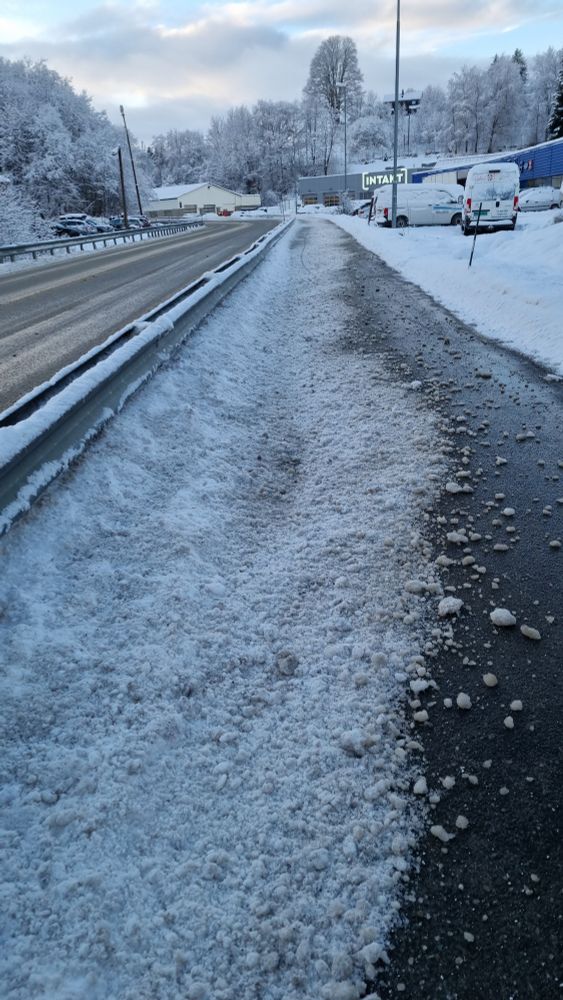 En gang- og sykkelvei. Et autovern skiller den fra veien ved siden av, men det har ikke vært nok til å stoppe spruten av hardpakket snø som har blitt kastet inn av en brøytebil og nå dekker mesteparten av bredden, bortsett fra et lite felt som er helt bart lengst vekk fra veien.
