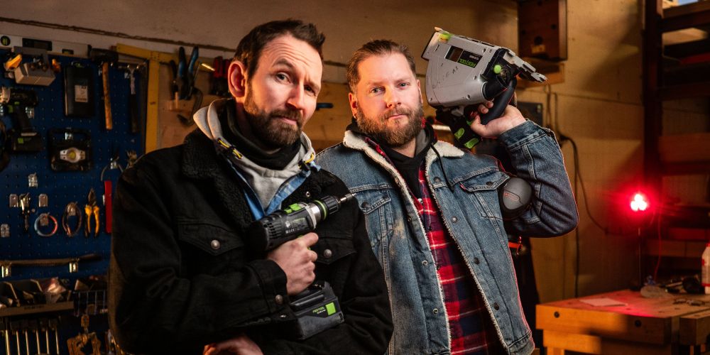 Snekker Kai Simon Simonsen og programleder Morten Strand fra "Mancave" på NRK. De står i arbeidsklær i en garasje med verktøy hengende på veggen i bakgrunnen. Kai Simon poserer med en drill, Morten holder en sirkelsag over skulderen.