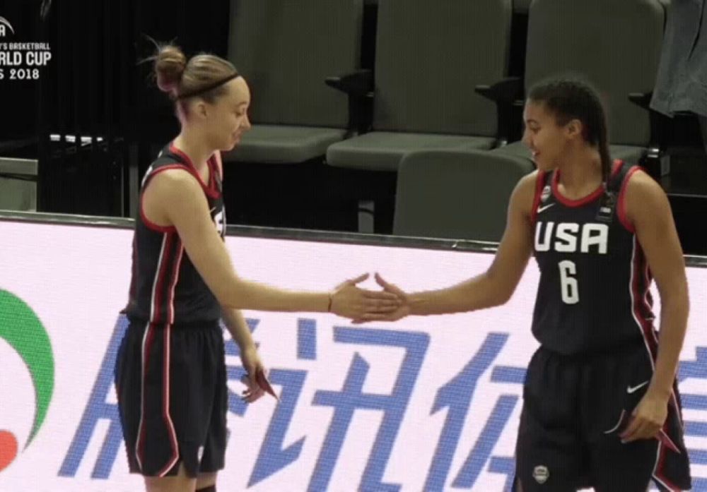 two female basketball players from the usa shake hands on the court