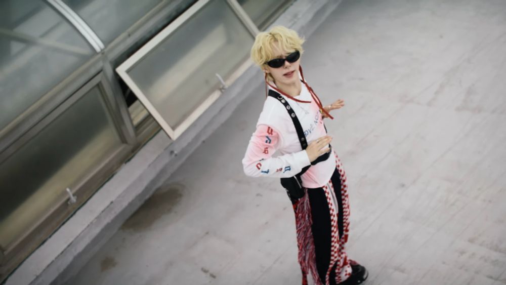 サングラスをかけているONEUSファヌン。白色のロングTシャツにハーネス、黒地に赤と白のチェッカー柄のデザインのあるボトムスを穿いている。