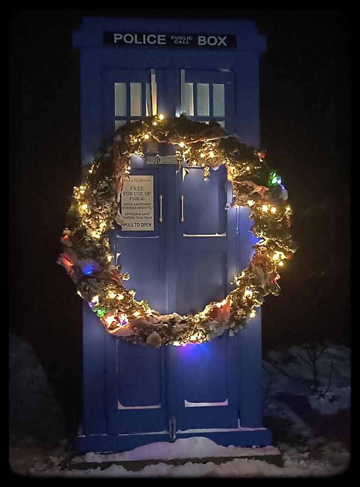 A blue police box with a Christmas wreath alight.