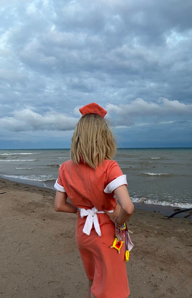 A cosplay of Rose Marigold looking towards the lake on the beach.