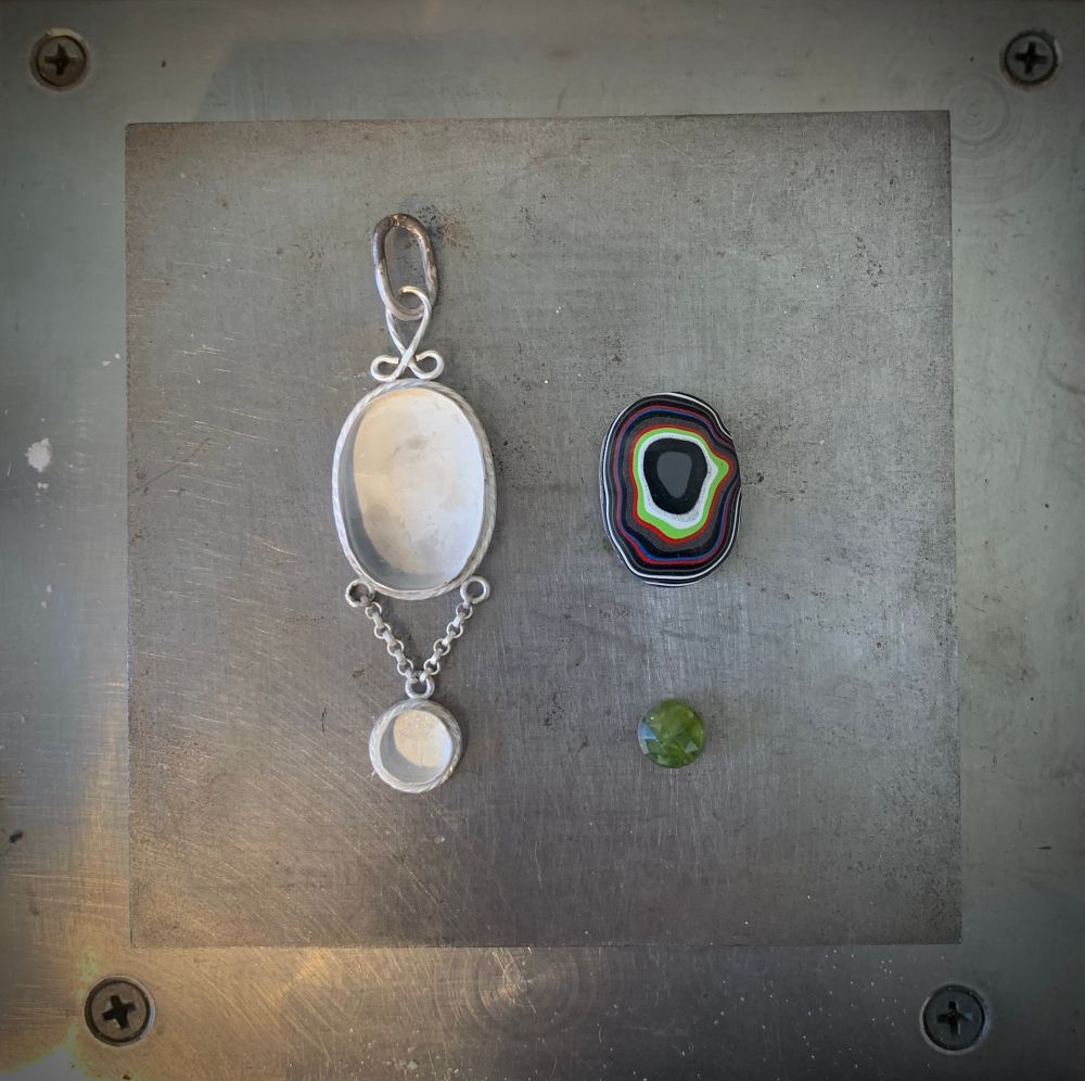 Silver pendant in progress with Fordite and vesuvianite cabochons to the right. 