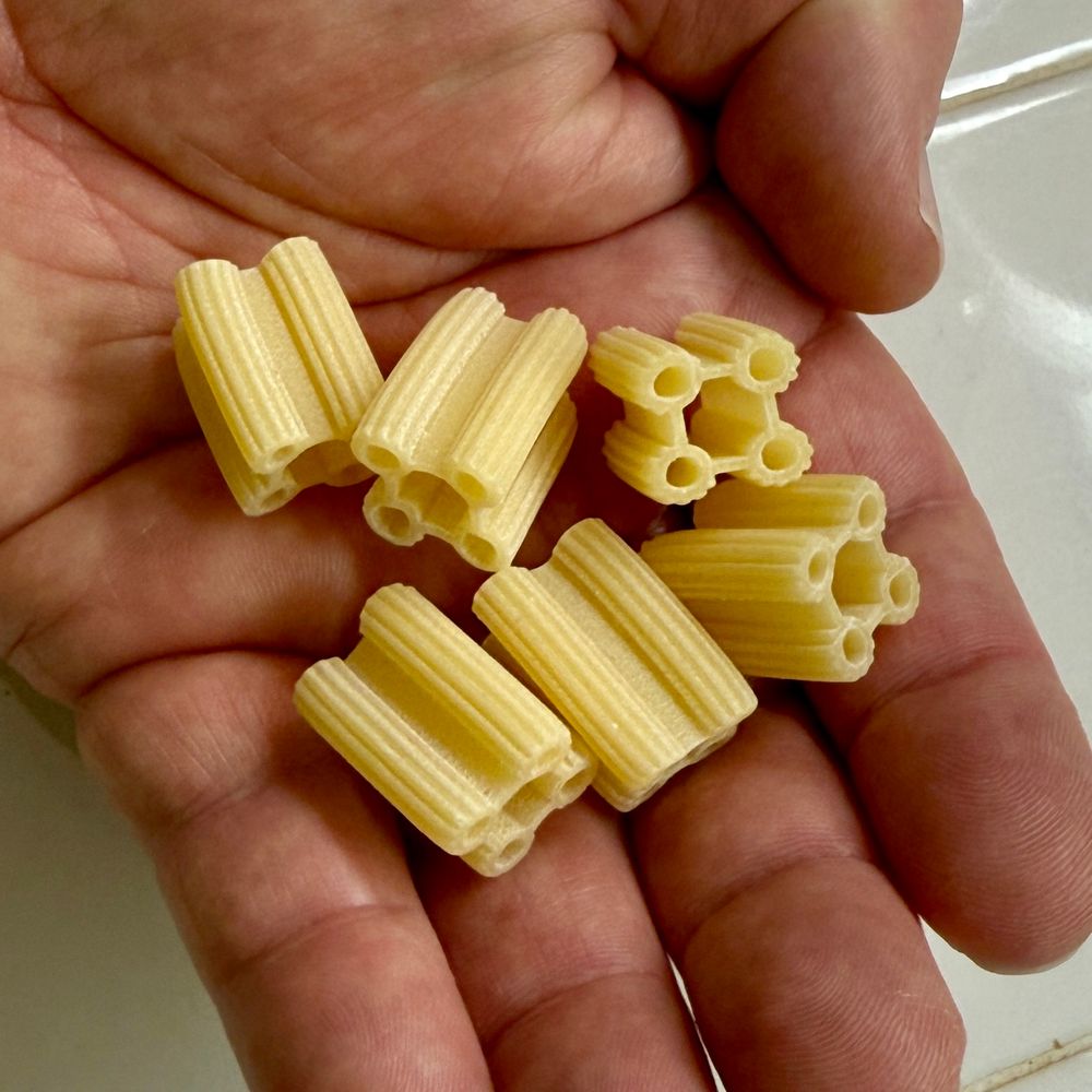 Five quattrotini pasta pieces in the palm of a hand. 
