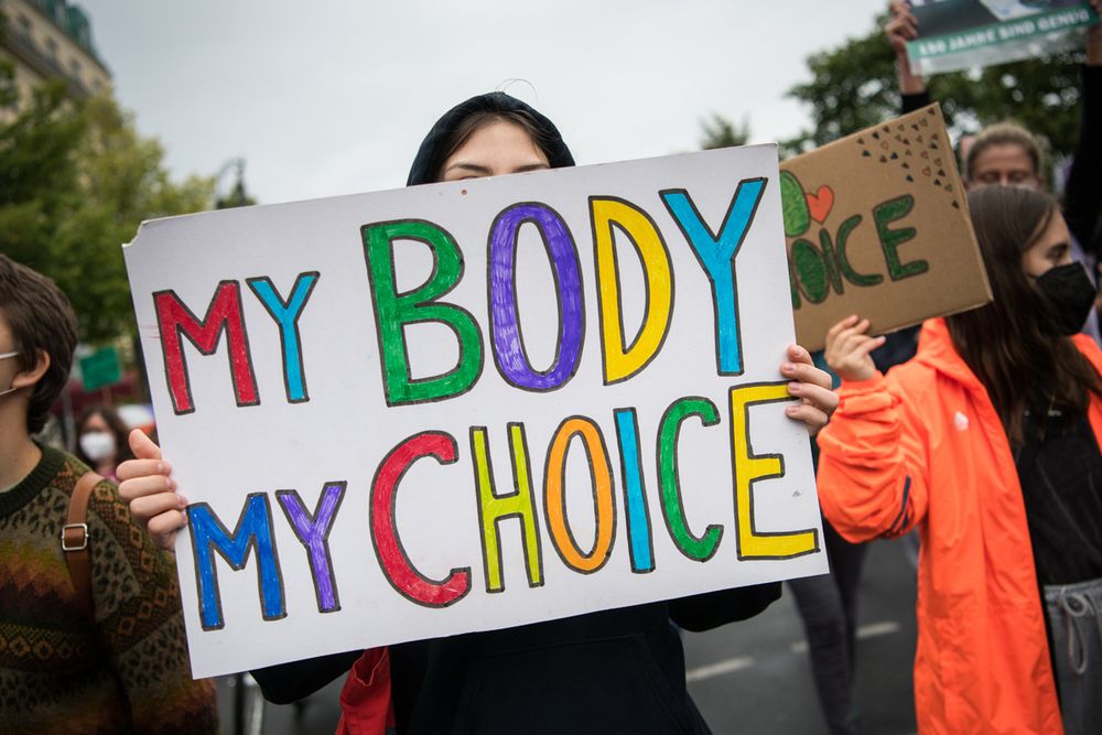 Eine Frau hält ein Schild mit der Aufschrift „My body my choice“