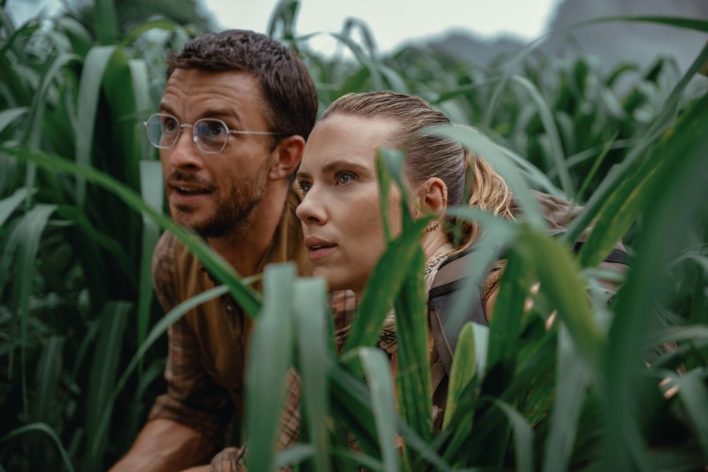 Screenshot from Jurassic Park: Rebirth.

Henry (Jonathan Bailey, left) and Zora (Scarlett Johansson) hide in some tall grass, as they stare in awe and wonder at a large dinosaur.