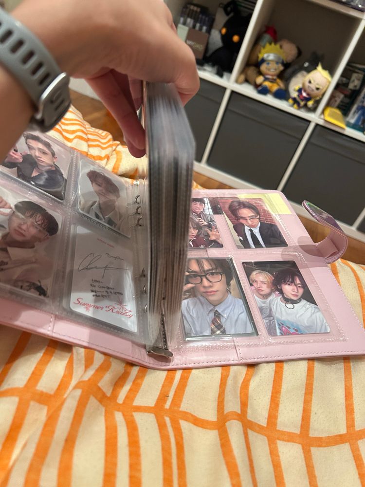 Pink photocard binder opened with basically all the middle pages held together to separate which pages are ateez. There’s like 3 pages of others before and after them because my life is a joke