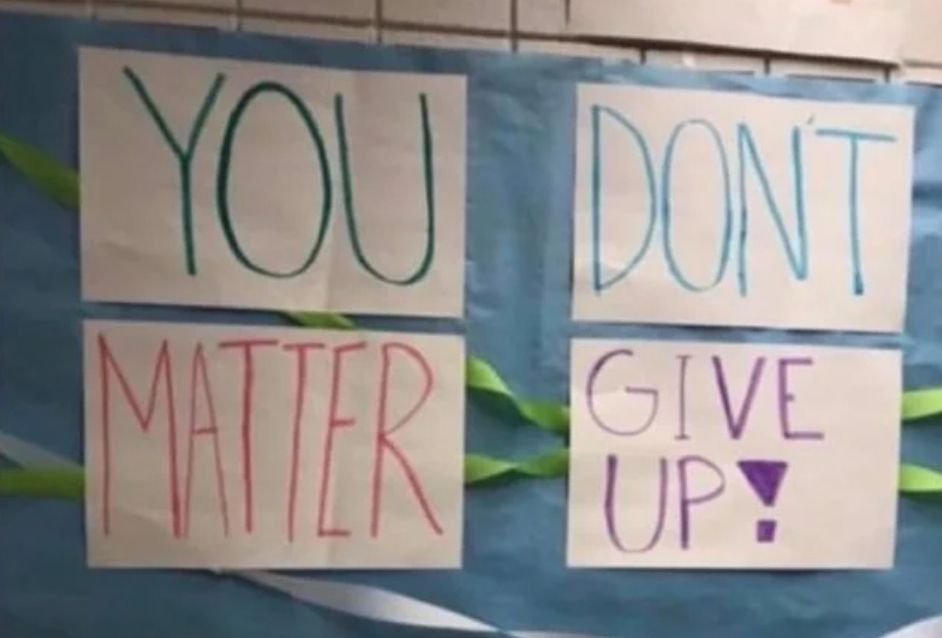 Handwritten signs taped to a window read, by rows: “YOU” “DON’T” and “MATTER” “GIVE UP!”