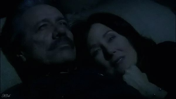 Bill Adama and Laura Roslin cuddling in the dark