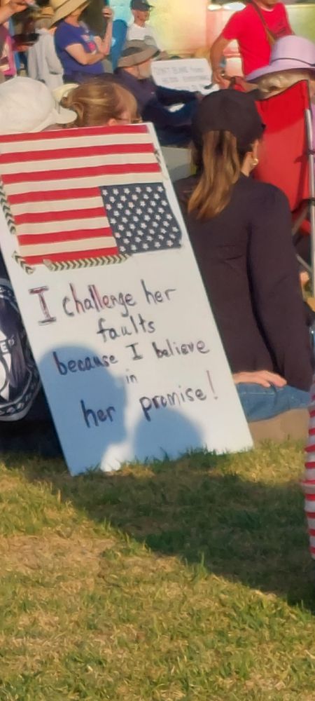 Sign with American flag in distress position "I challenge her faults because I believe in her promise"