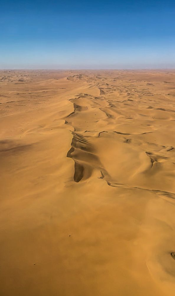 Flug über die Wüste. Zu sehen sind große Sanddünen die von Westen nach Osten verlaufen. 