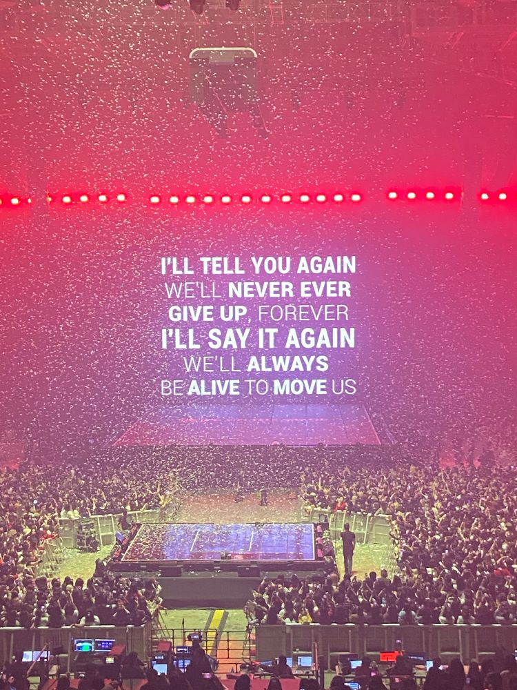 Red stage with lyrics from j-hope’s song, Neuron - “I’ll tell you again, we’ll never ever give up forever, I’ll say it again, we’ll always be alive to move us.”