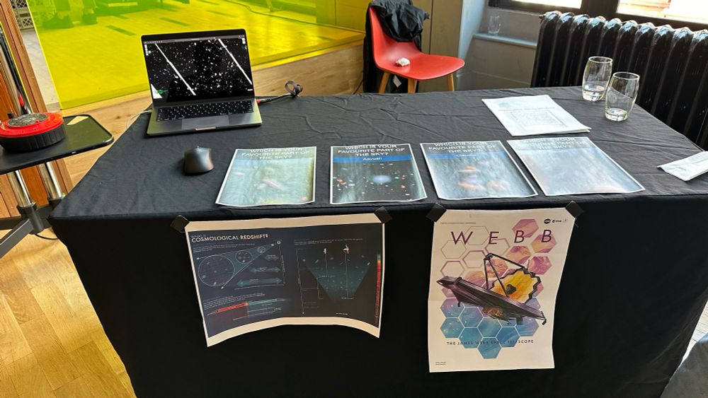 JWST activity table showing posters of galaxies and a laptop