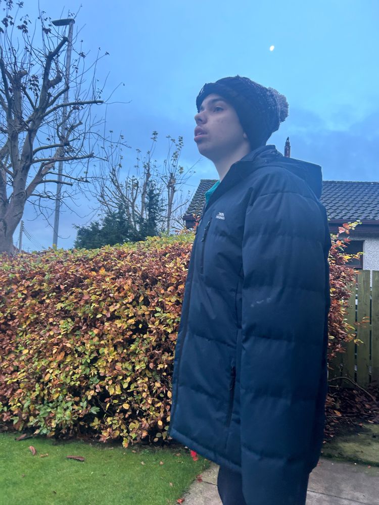 Joe waiting for his bus wrapped up in a big coat and Willy hat