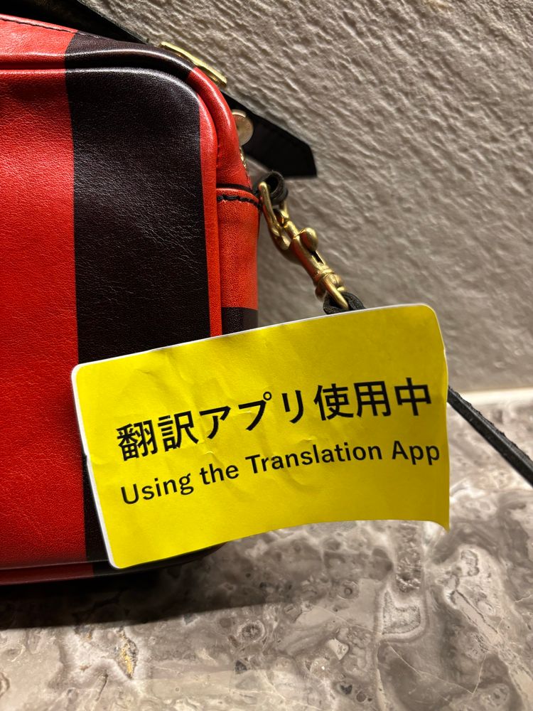 A sticker that has Japanese writing with an English translation that says “using the translation app”. 