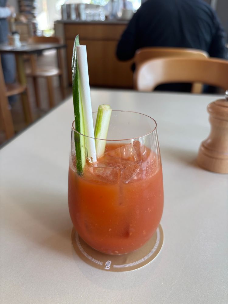 A glass of tomato juice and booze decirated with a cucumber & a celery slice. 