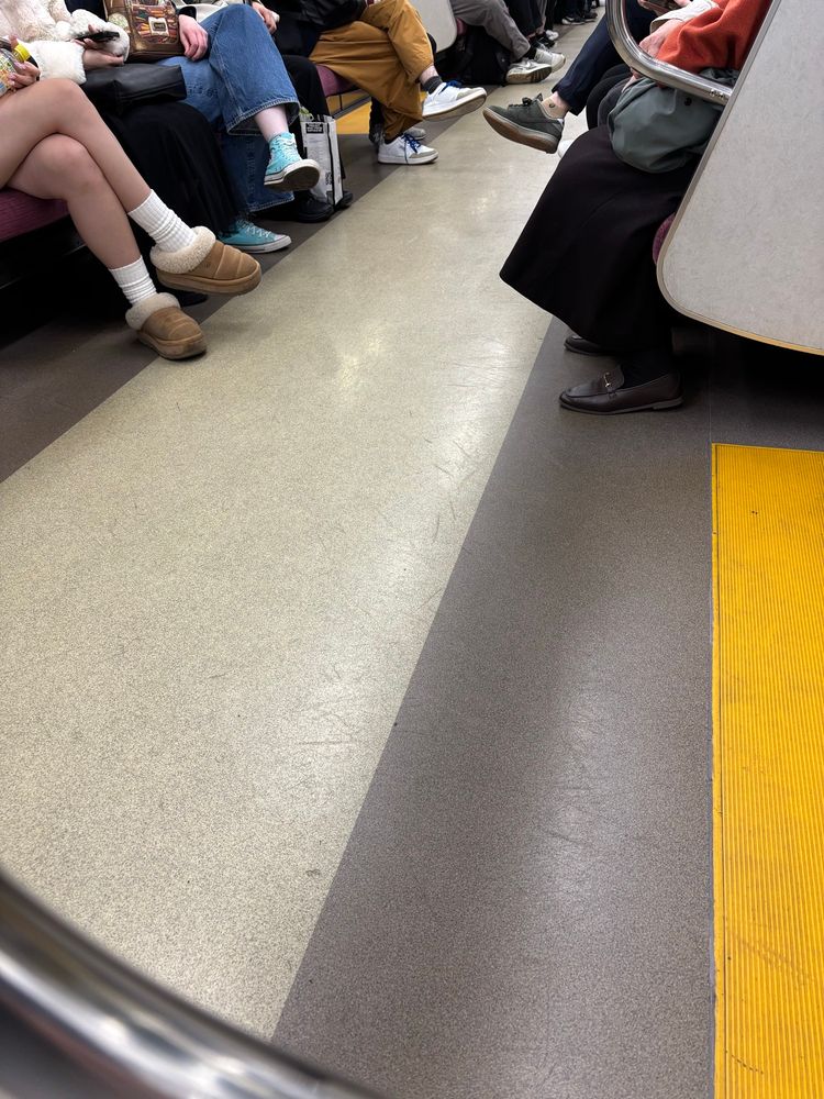 The floor of a train. People’s feet visible. Japan. Shinjuku line. 