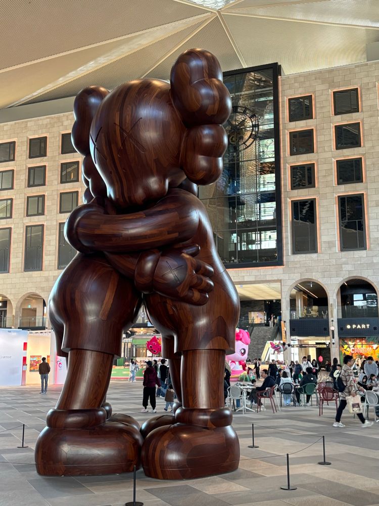 Enormous wooden bear creatures embrace. Art. KAWS. “Embrace”