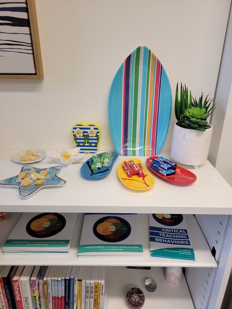 A shelf in the Syracuse Center for Teaching and Learning Excellence featuring some summery decorative items, like flip flop and star fish candy dishes.