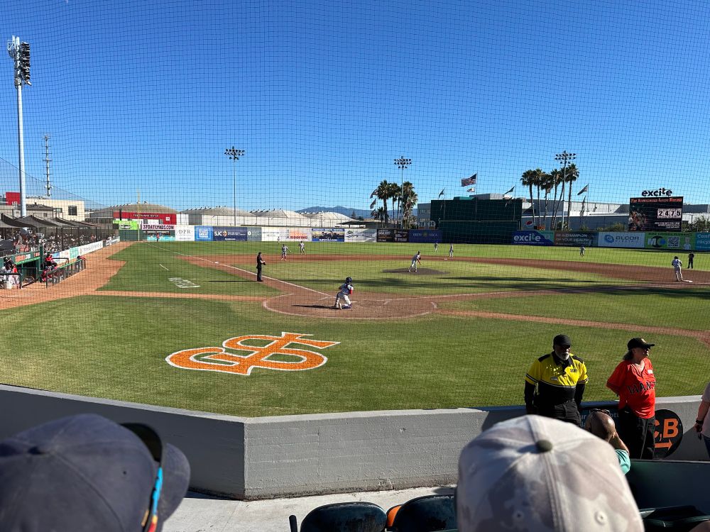 A picture from behind home plate of the San Jose Giants field while the Stockton Ports catcher takes a warmup pitch from the Ports pitcher. 