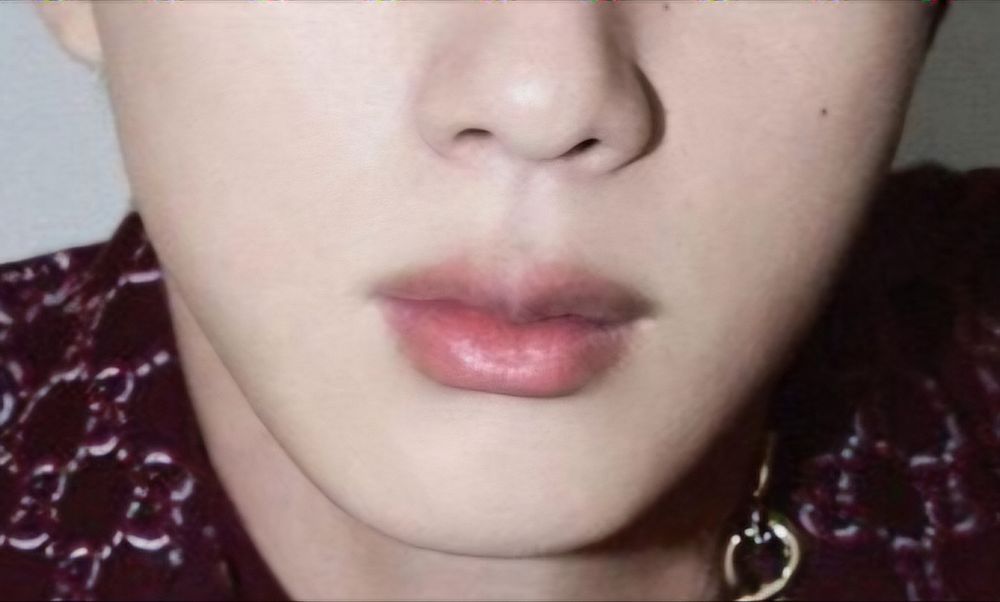 Close up of Jin's lips with a bit of maroon patterned suit showing
