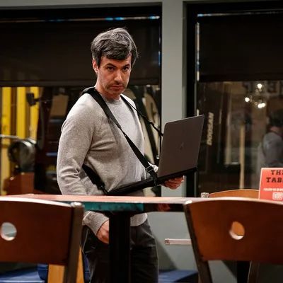 Nathan Fielder with a laptop strapped to his chest, staring intensely at a subject offscreen