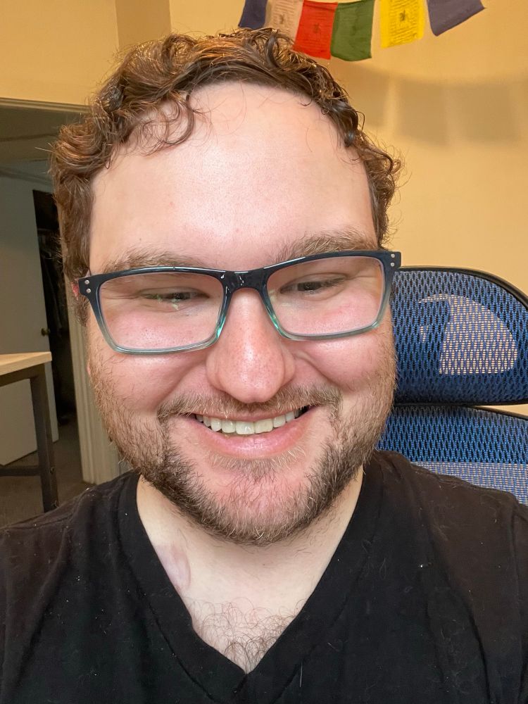 Selfie of man smiling in blue framed rectangular glasses