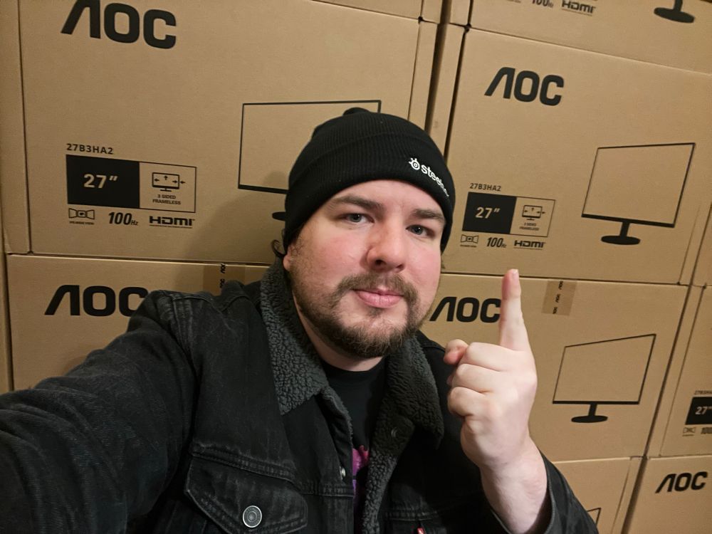 A man posing in front of 16 monitors