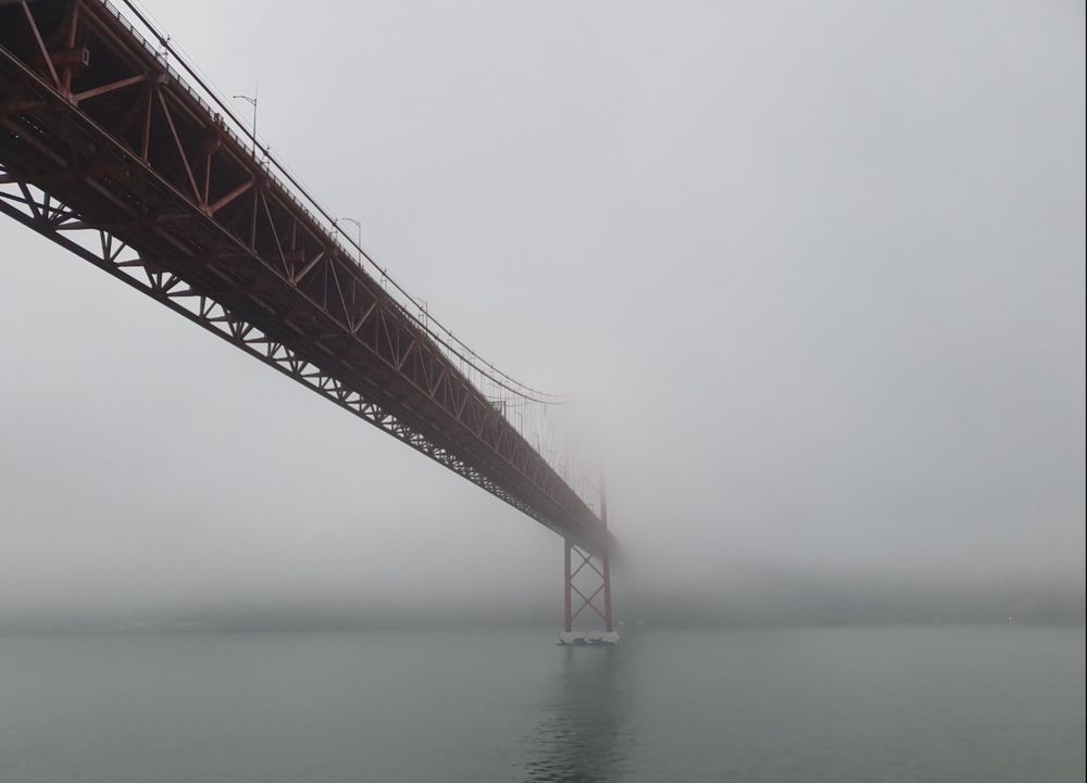 Brücke des 25. April über den Tejo in Lissabon/Portugal. Die Hälfte der Brücke und das gegenüber liegende Ufer mit der Stadt verschwindet in dichtem, grauen Nebel