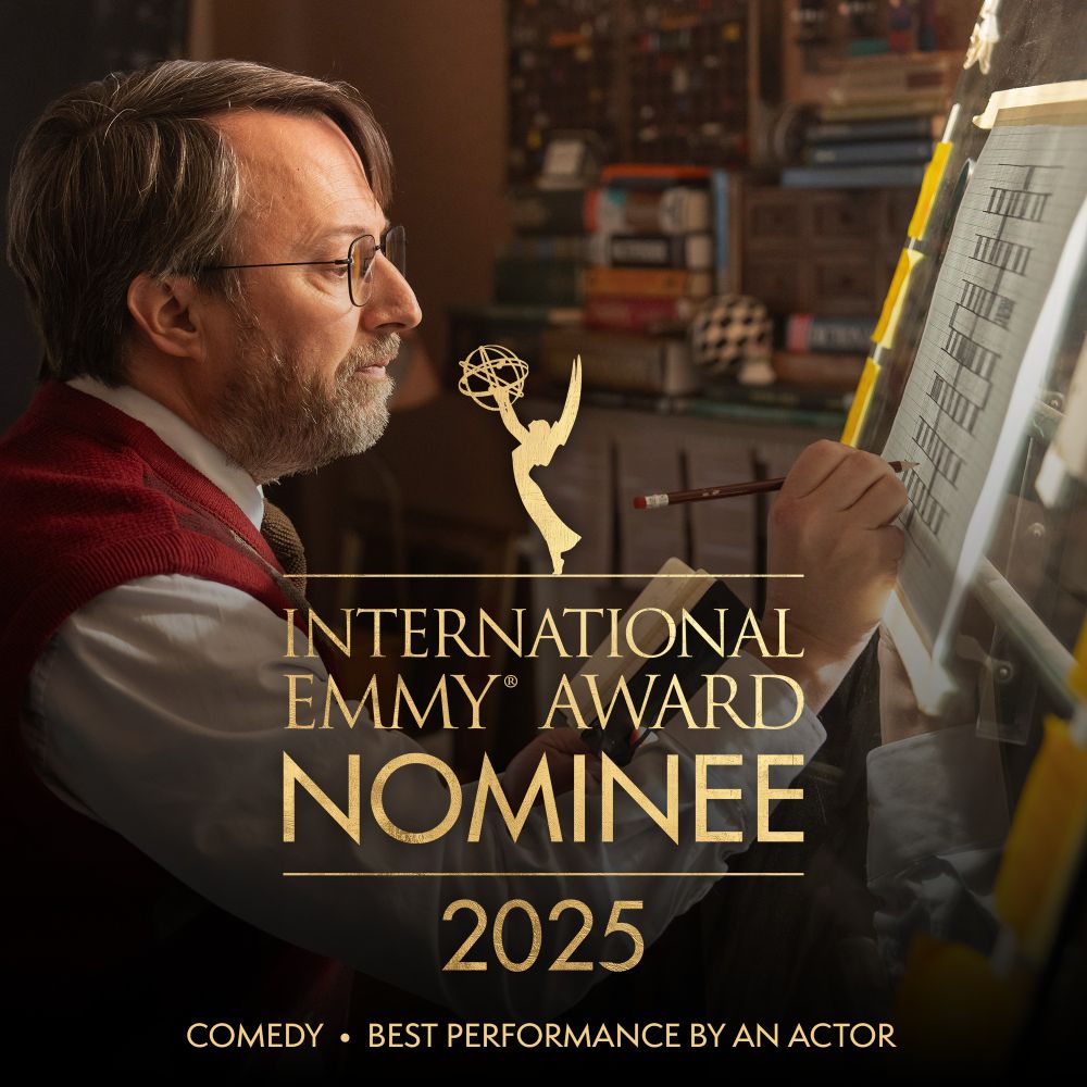 Image of David Mitchell designing a crossword in the show Ludwig. Overlaid is the Emmy logo, with text reading, 'International Emmy Award Nominee 2025, Comedy and Best Performance by an Actor'.