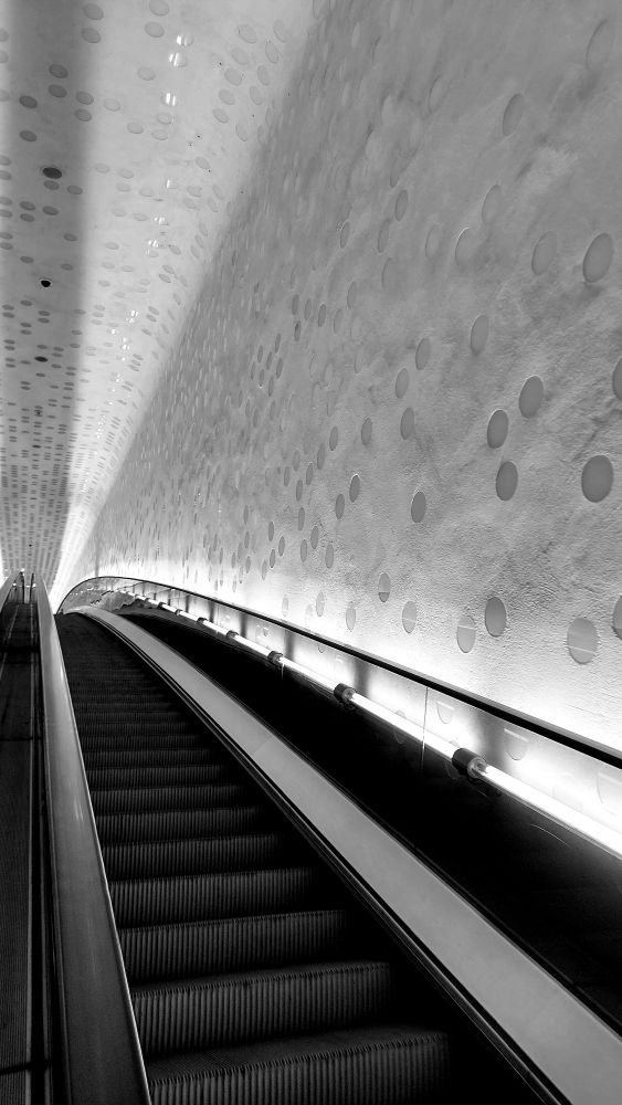 Eine menschenleere lange Rolltreppe von unten fotografiert. Schwarzweiß Foto 