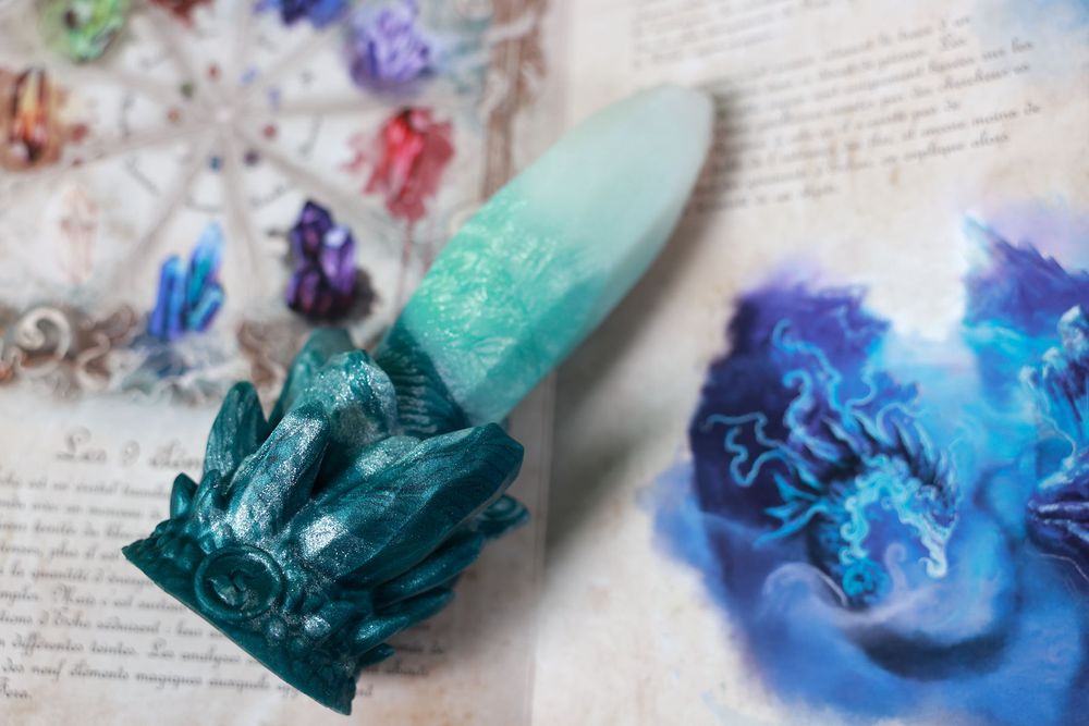 Photo of Fera Daemon's Echo dildo lying on the Echo Illustration optional artwork. Sydney has just posted a full review of the Echo dildo on their blog: https://sydneyscreams.com/category/blog/ 