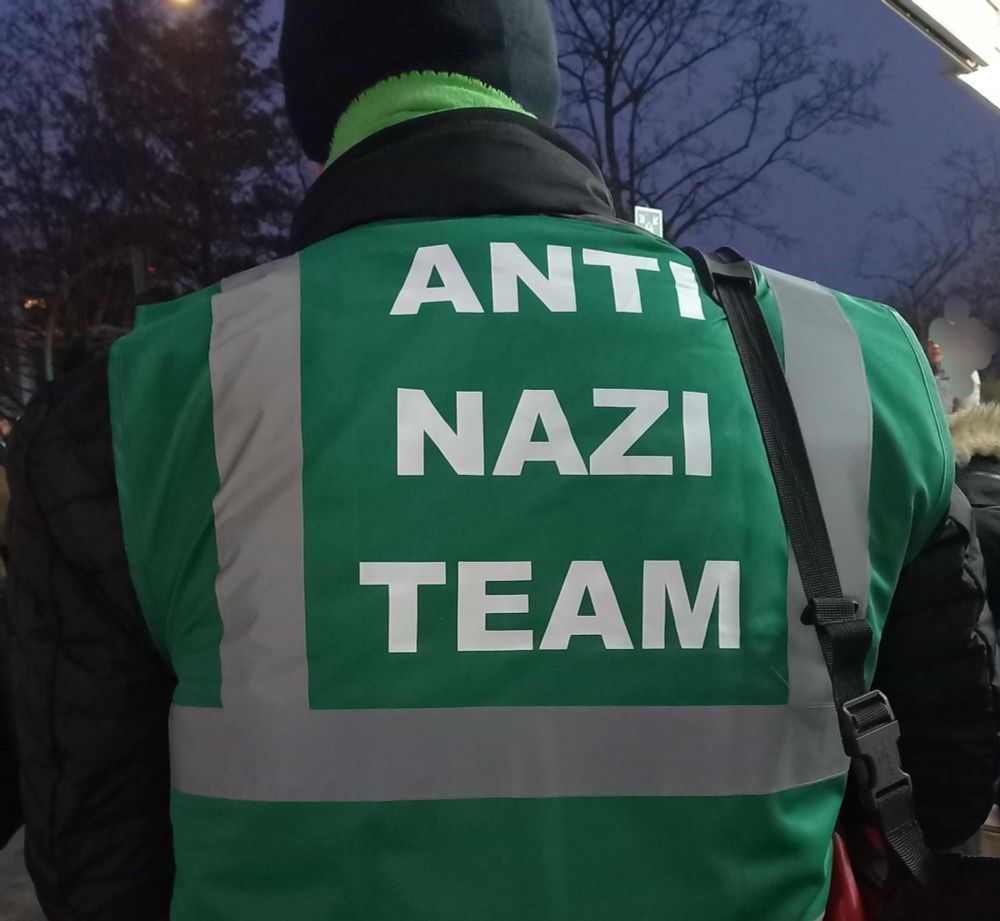 Foto des Rückens einer grünen Weste mit weißer Schrift "Anti Nazi Team'