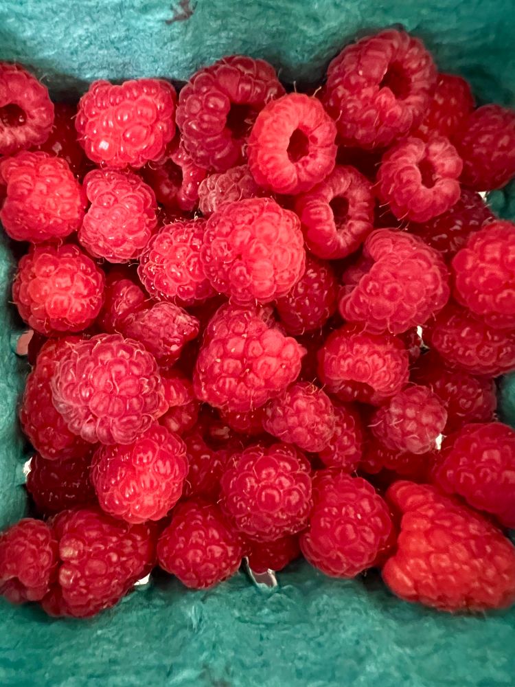 A container full of red raspberries 