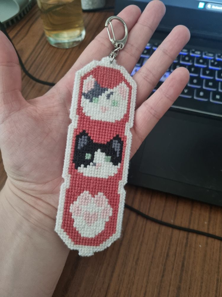 Porte clef brodé avec deux têtes de chats et une patte de chat au bout 