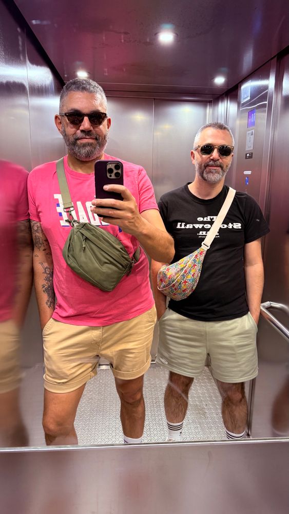 Photo de Fred et mo dans l’ascenseur. Je porte un magnifique t-shirt rose avec l’inscription « PÉDALE » et Fred un t-shirt noir à l’effigie du Stonewall inn de New-York 
