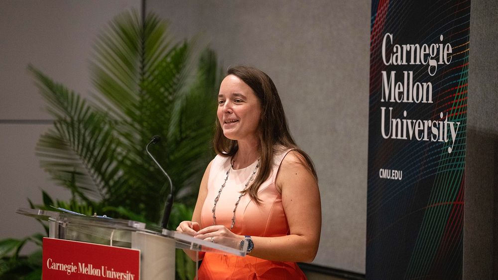 Diana Parno stands at a podium and gives a speech. A banner in the background says "Carnegie Mellon University."
