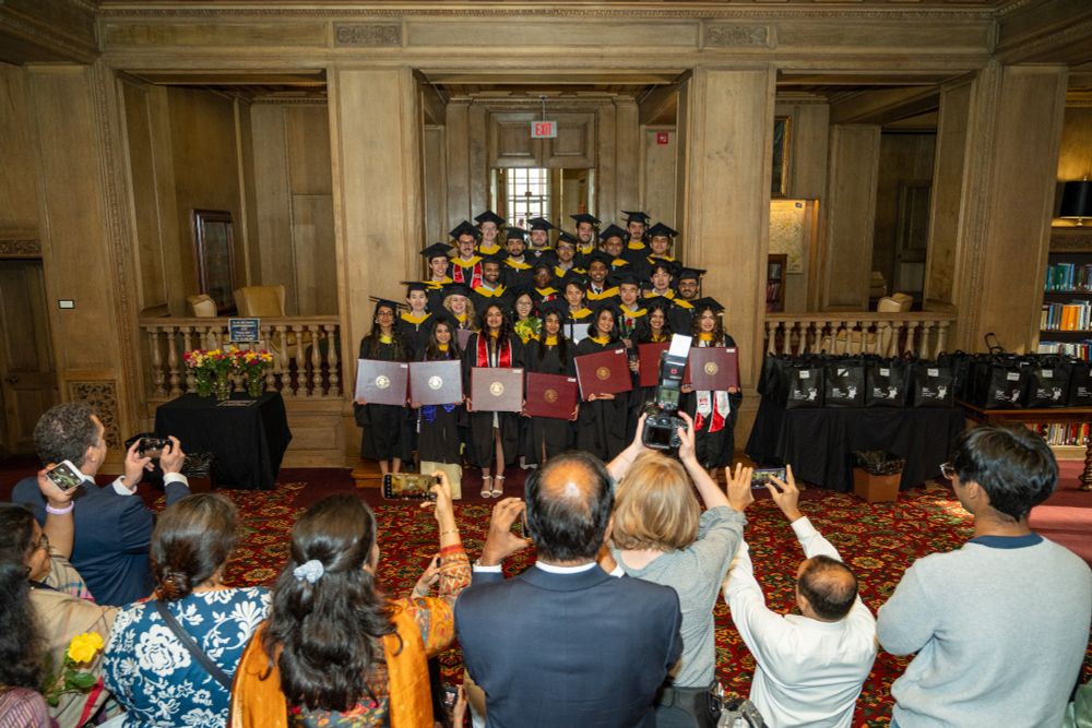 MS-DAS students stand on the steps of the Mellon Institute Library holding their diplomas as their friends and families take photos.