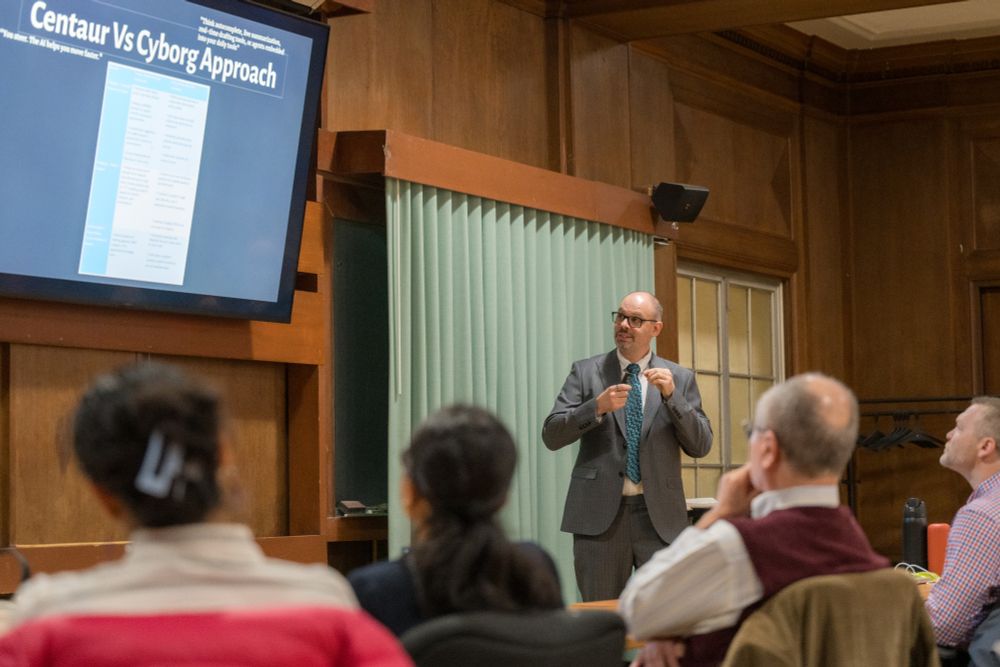 Simon Faulkner looks at a screen in a classroom as he explains a concept to a room full of professors.