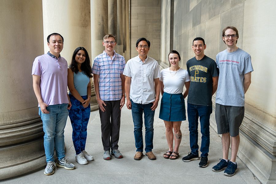 Yisong Guo (center) and six members of his lab stand outside of Mellon Institute.