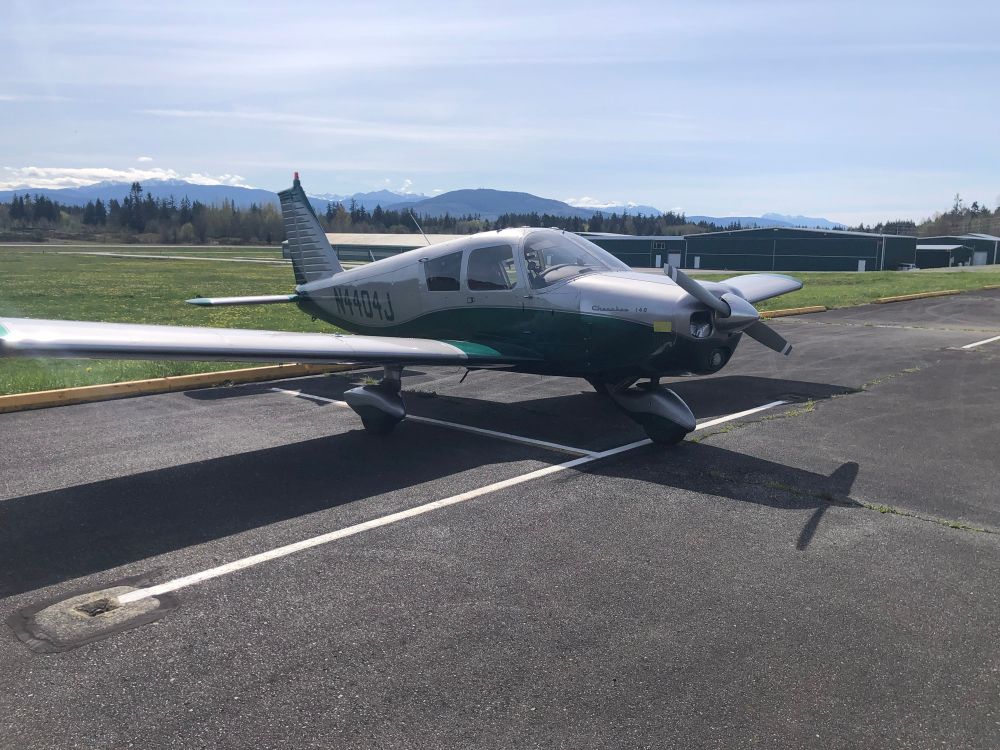 A Piper Cherokee 140 in silver with green. A four seat airplane.  N4404J