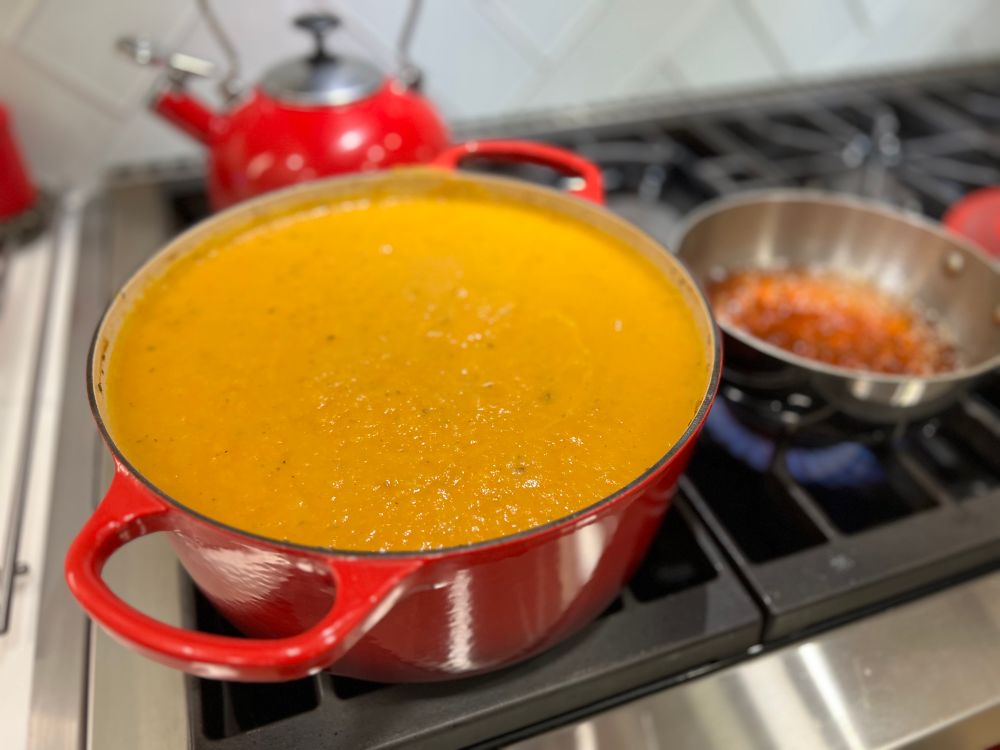 Orange puréed soup with apple cider reducing alongside 