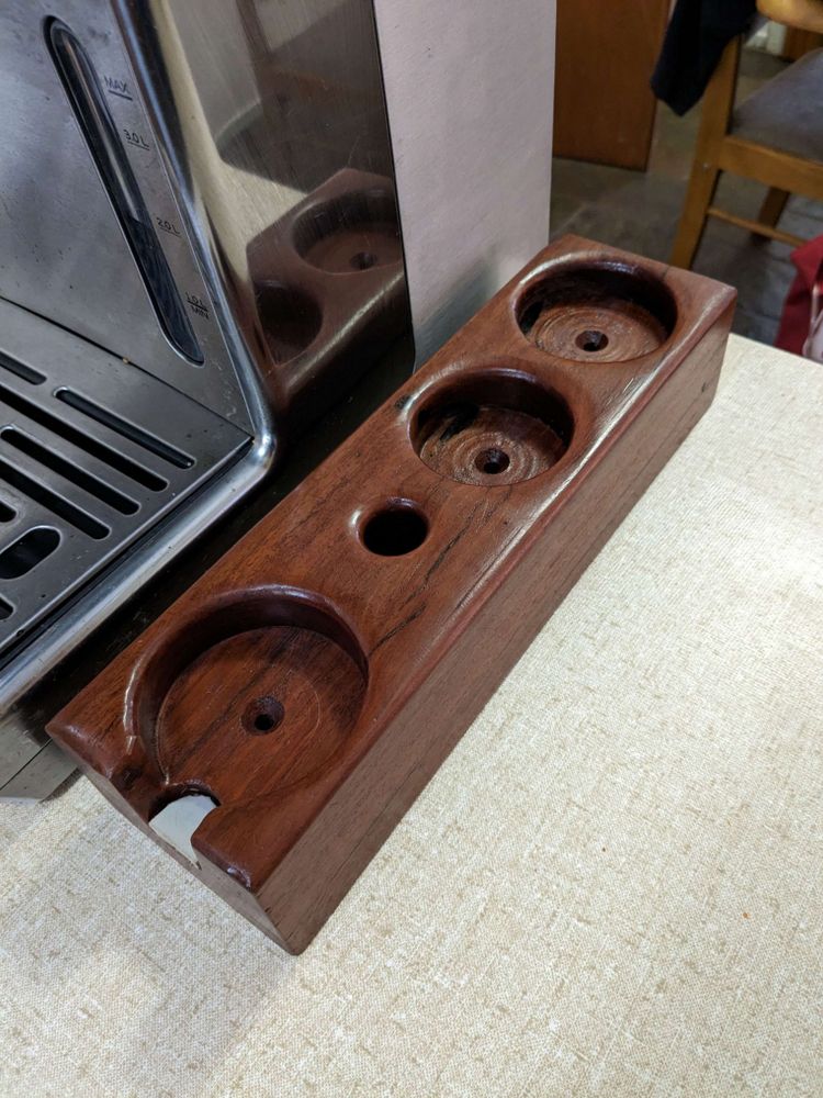 A solid wooden block of Australian Red Gum with various holes drilled in it to fit coffe-making tools.