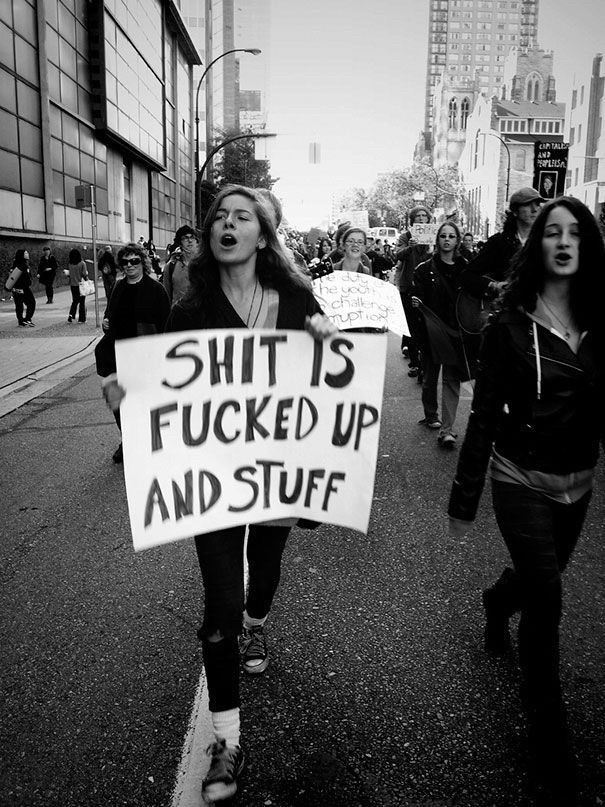 Protester carrying a sign that says, "Shit is fucked up and stuff."