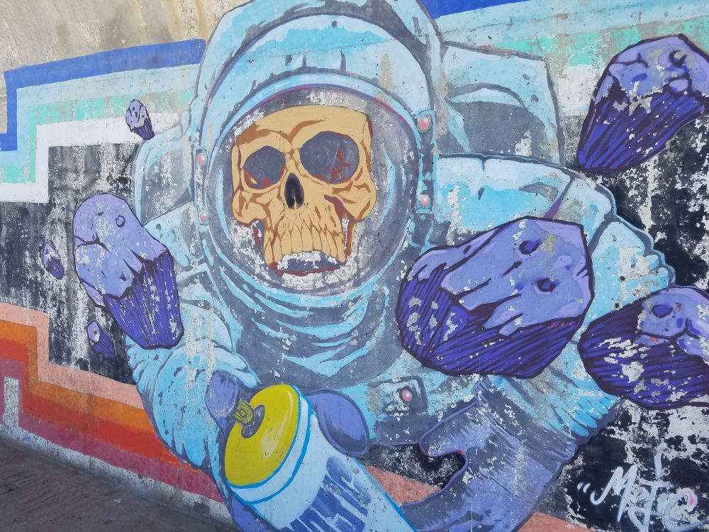 Graffiti of a skeleton wearing a space suit doing graffiti 