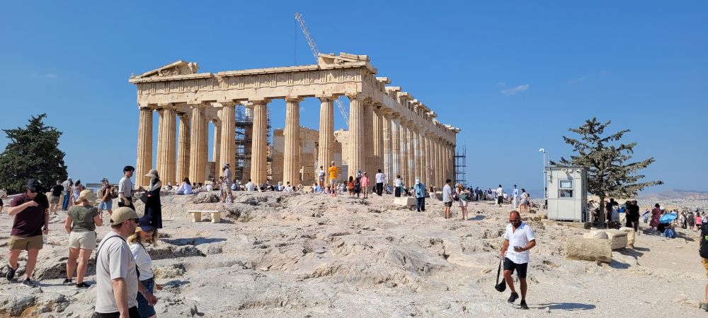 A view of the Parthenon surrounded by a crowd of tourists.